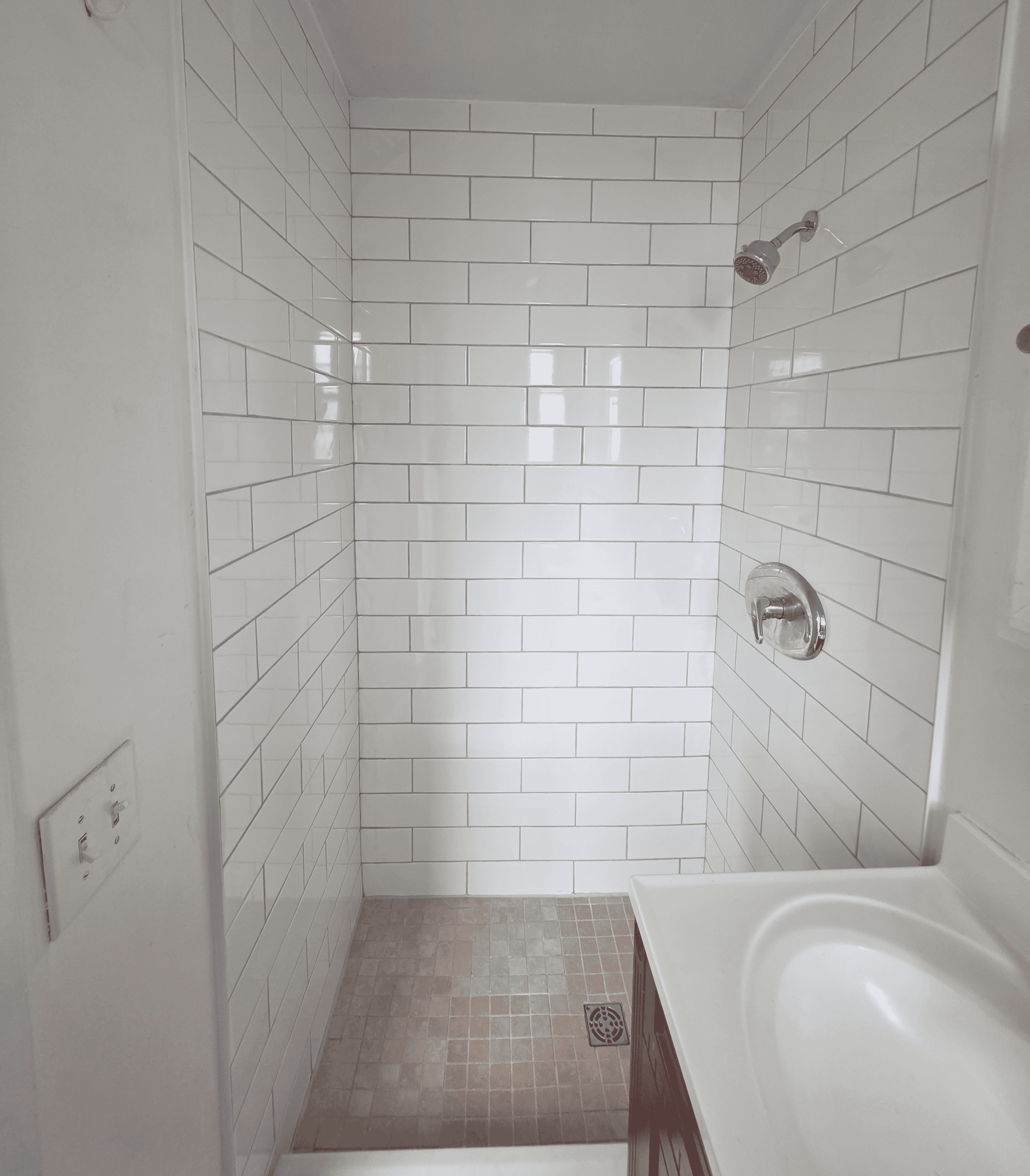 Example Co shower with white subway tiles and a beige tiled floor.