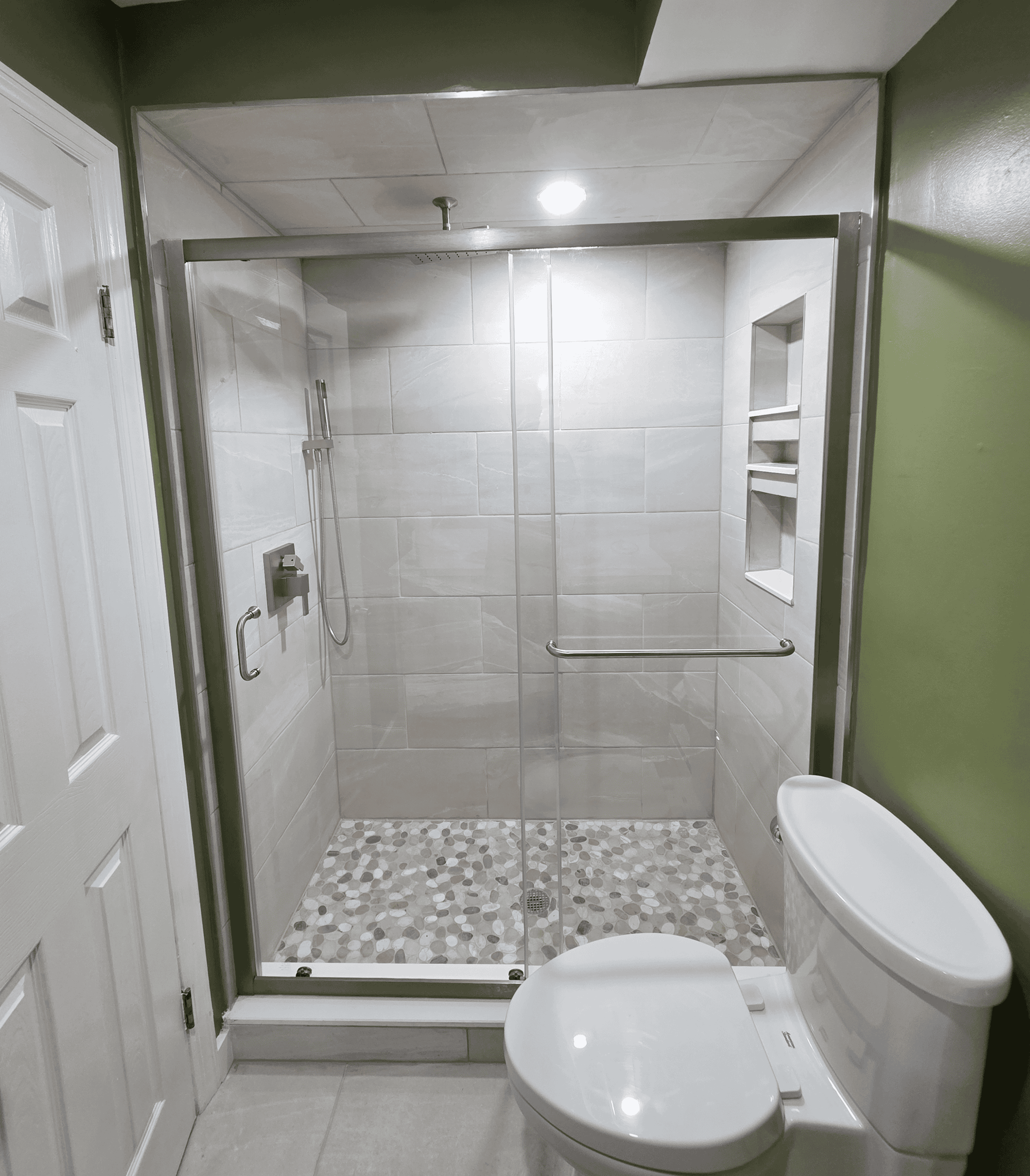 Bathroom shower with glass enclosure and accessibility bar.