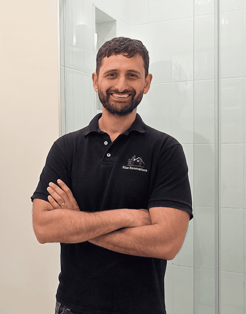 Example Co team member with arms crossed in black polo at Example Co showroom.