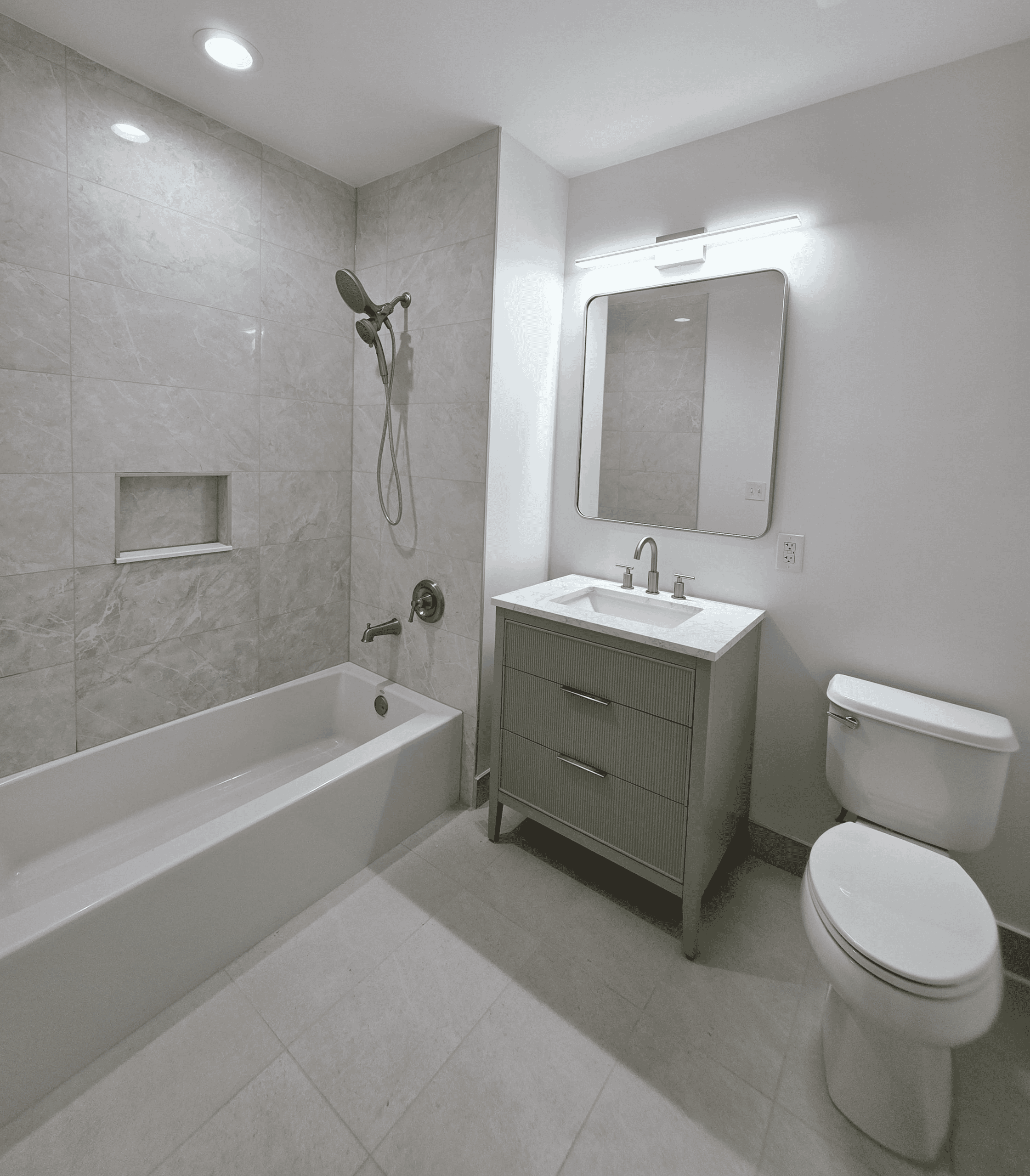 Modern bathroom with tub, shower, vanity and toilet in a neutral color palette.